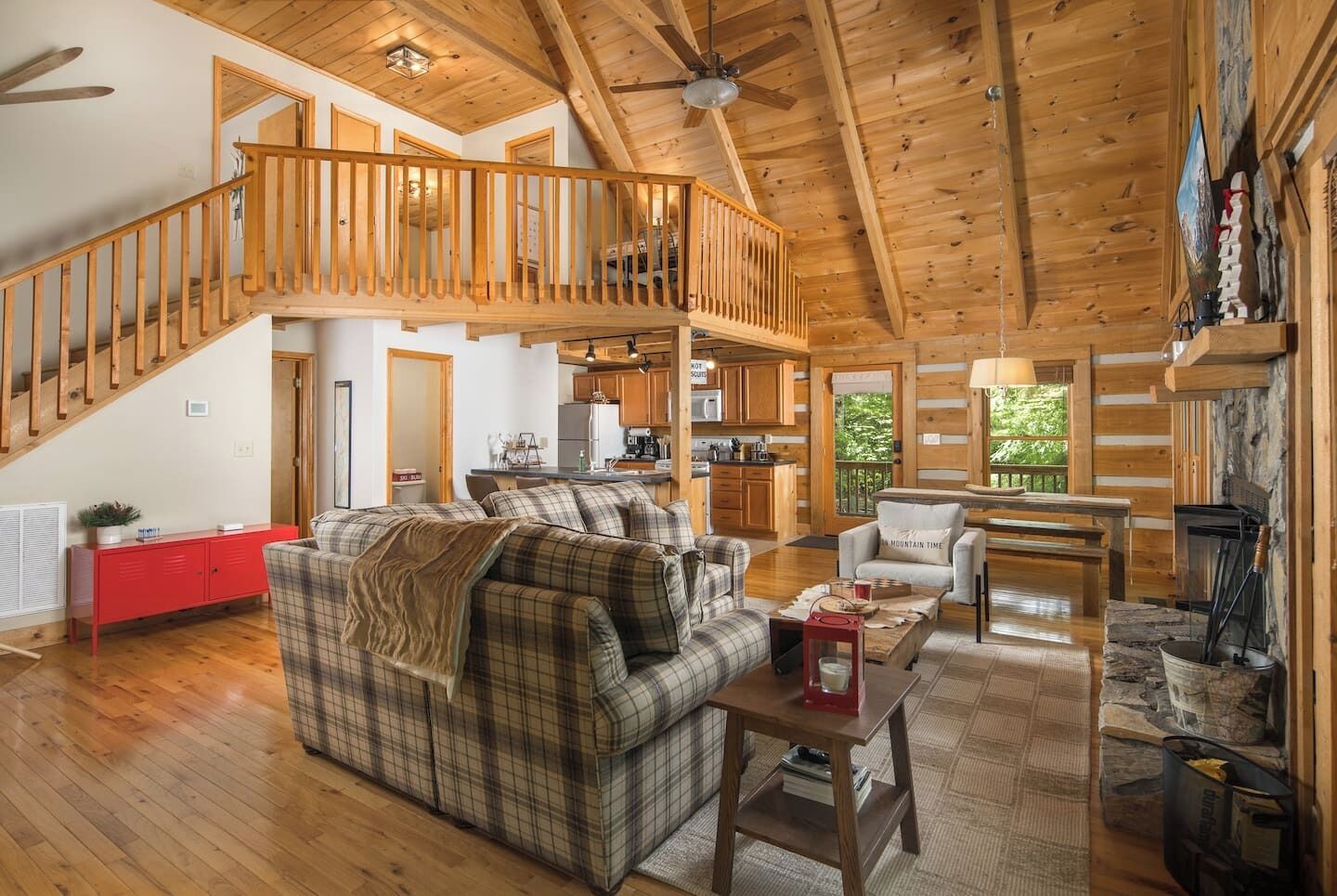 This warm and inviting great room features soaring vaulted ceilings, exposed beams, and floor-to-ceiling windows that bring the outdoors in.