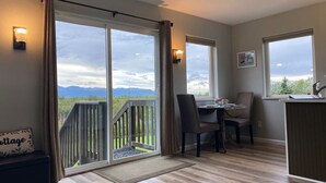Une pièce dotée d’une porte-fenêtre coulissante donnant sur un balcon, d’un coin repas avec des chaises, d’une petite table et d’un comptoir de cuisine.