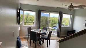 A dining area with a table and chairs, a view of the outdoors, and a ceiling fan. - Fireweed Cottage Alaska at your doorstep! (Palmer)