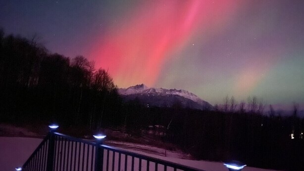 A snowy landscape with a mountain in the background and a railing with lights. - Fireweed Cottage Alaska at your doorstep! (Palmer)