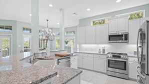 A modern kitchen with granite countertops, stainless steel appliances, and white cabinetry. - Tivoli by the Sea 5286 (Miramar Beach)