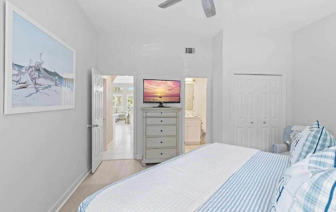 Une chambre à coucher avec un lit, une commode, un téléviseur et une porte.