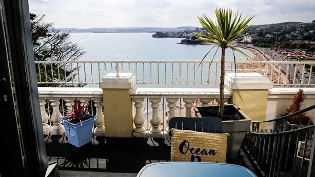 A balcony with a view of a beach and the sea.
