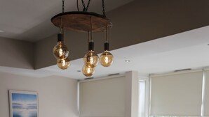 A modern dining area with a glass table, white chairs, and a chandelier.