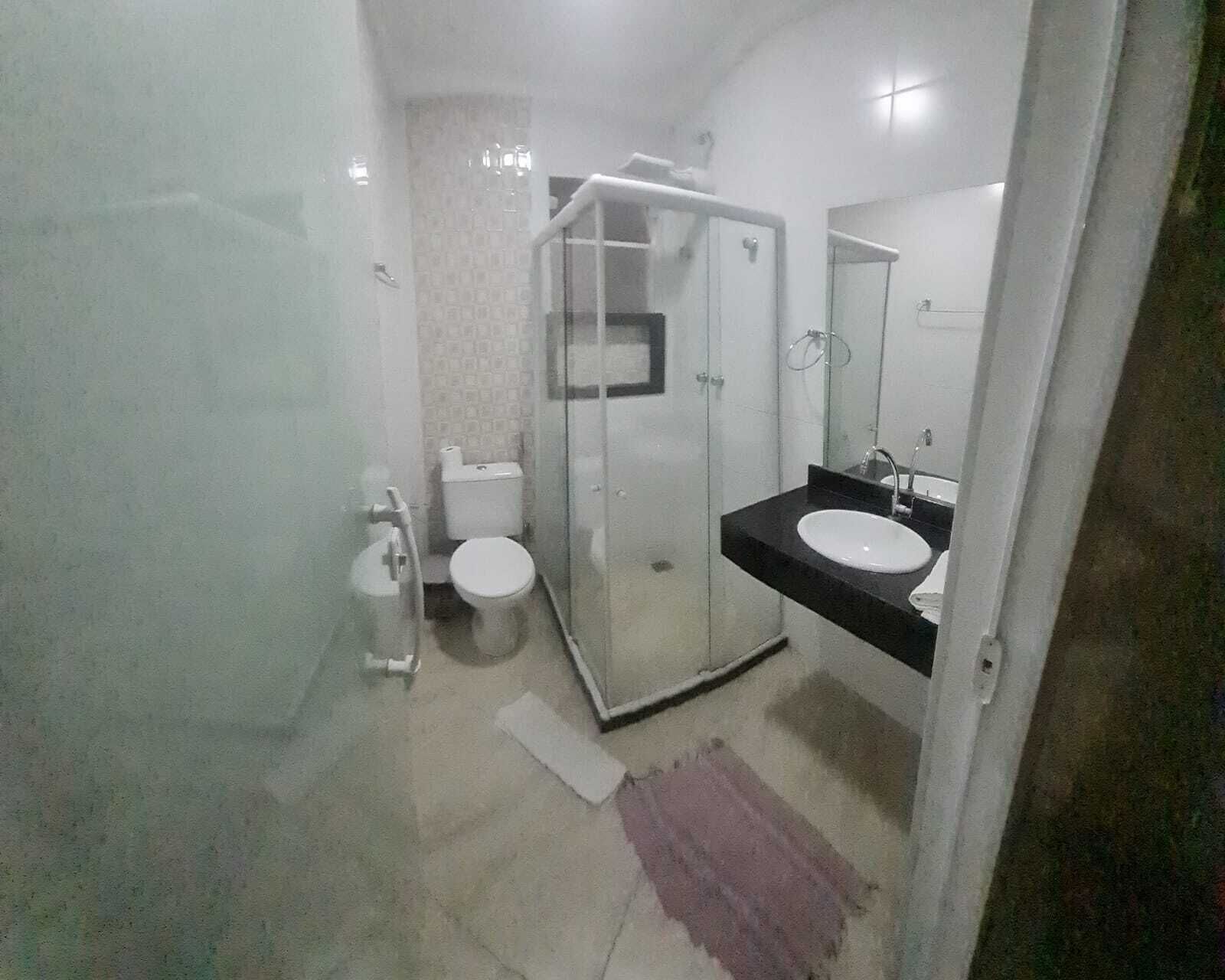 A modern bathroom with a glass-enclosed shower, a toilet, and a sink with a mirror.