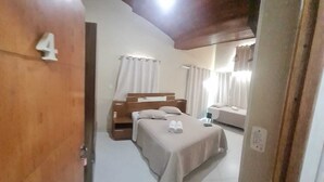 A bedroom with a bed, a bedside table, and a window with curtains.