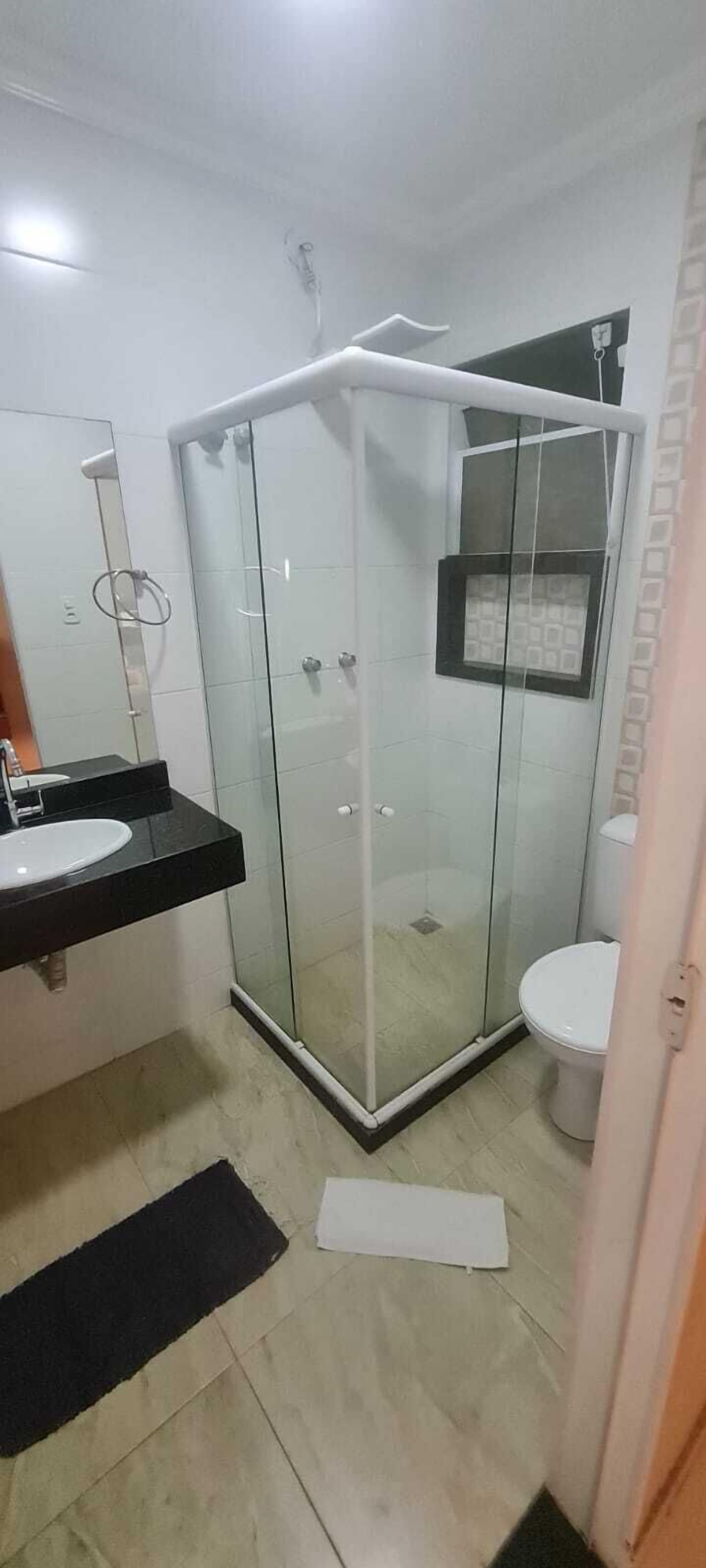 A bathroom with a glass-enclosed shower, a white toilet, and a black countertop with a sink.