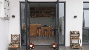 A modern interior with a reception desk, bar stools, and a shelf with plants. - Wudaoqing Guesthouse (Shengsi)