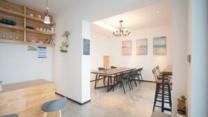 A modern dining area with a wooden table and chairs, a chandelier, and artwork on the walls. - Wudaoqing Guesthouse (Shengsi)