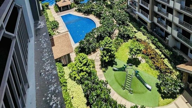 A residential building with multiple balconies, a swimming pool, and a children's playground. - OYO 1171 Raja Alea Residences (Bacoor City)
