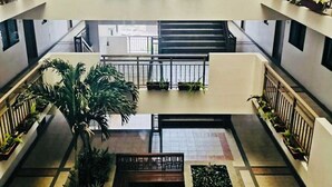 A multi-level atrium with balconies, potted plants, and a central staircase. - OYO 1171 Raja Alea Residences (Bacoor City)