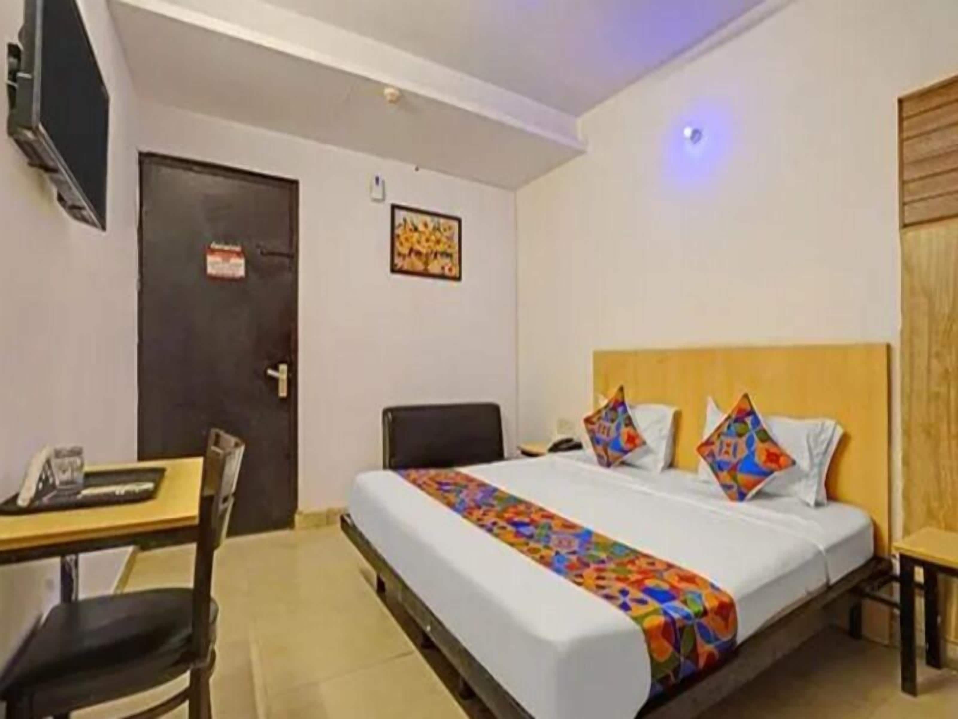 Ein Hotelzimmer mit Bett, Schreibtisch, Stuhl und Fernseher.