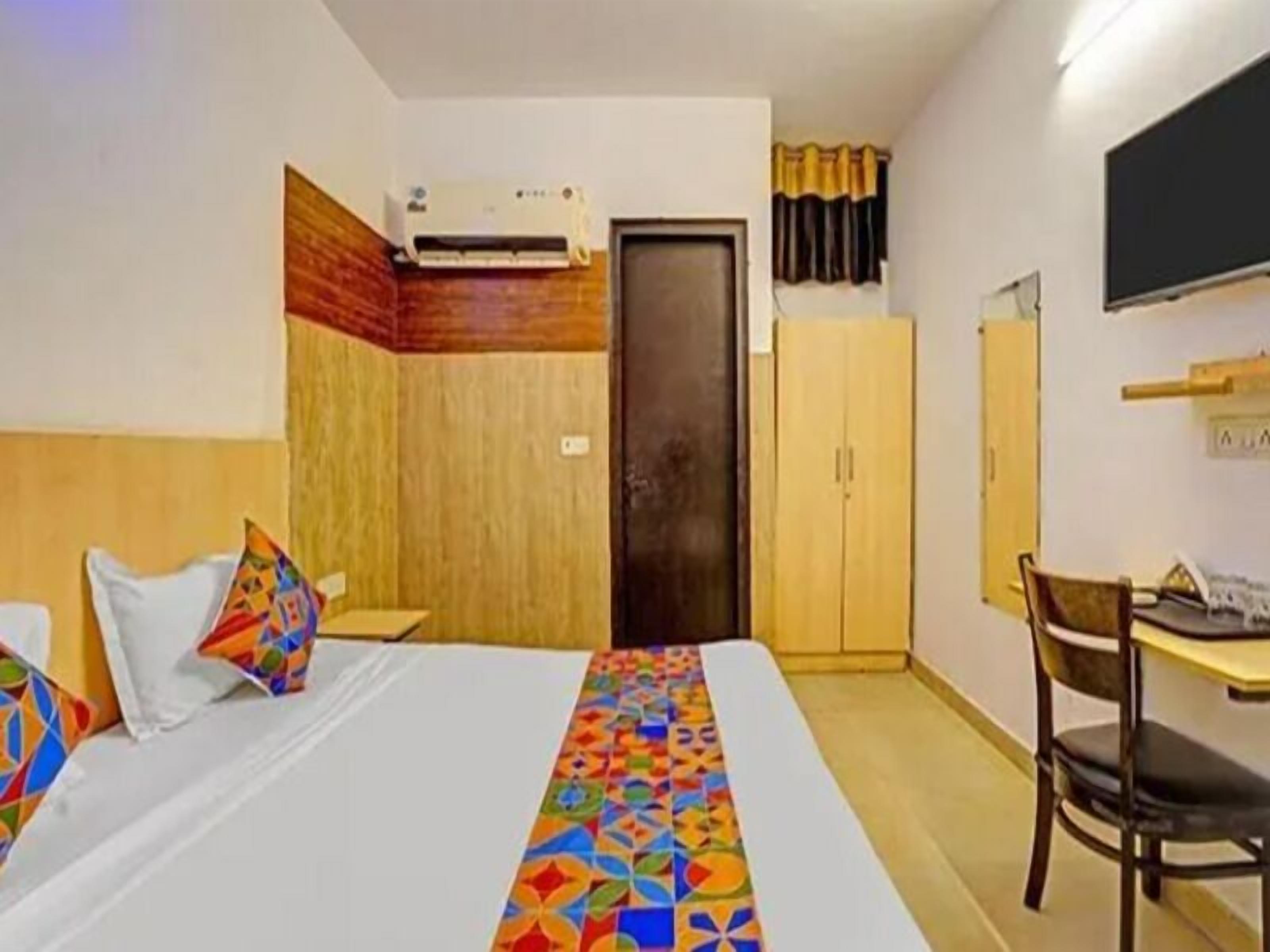 Une chambre d’hôtel équipée d’un lit, d’un bureau, d’une chaise, d’un climatiseur et d’une armoire.