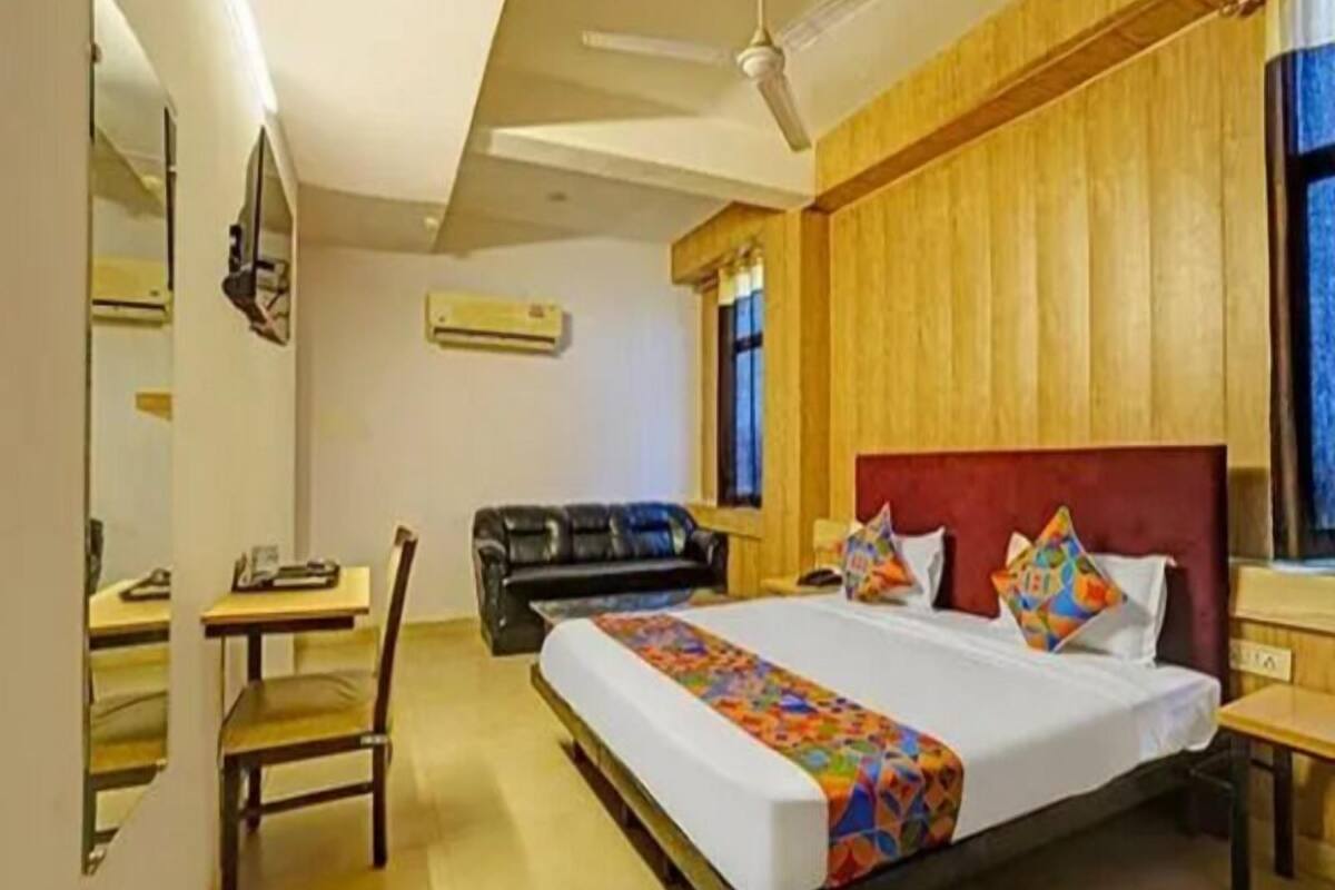 Quarto de hotel com uma cama grande, uma escrivaninha, uma cadeira e uma janela.