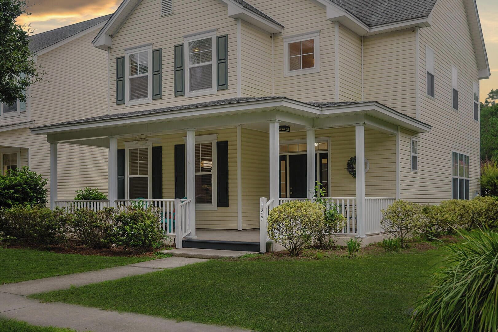 A two-story house with a covered porch and a front yard.