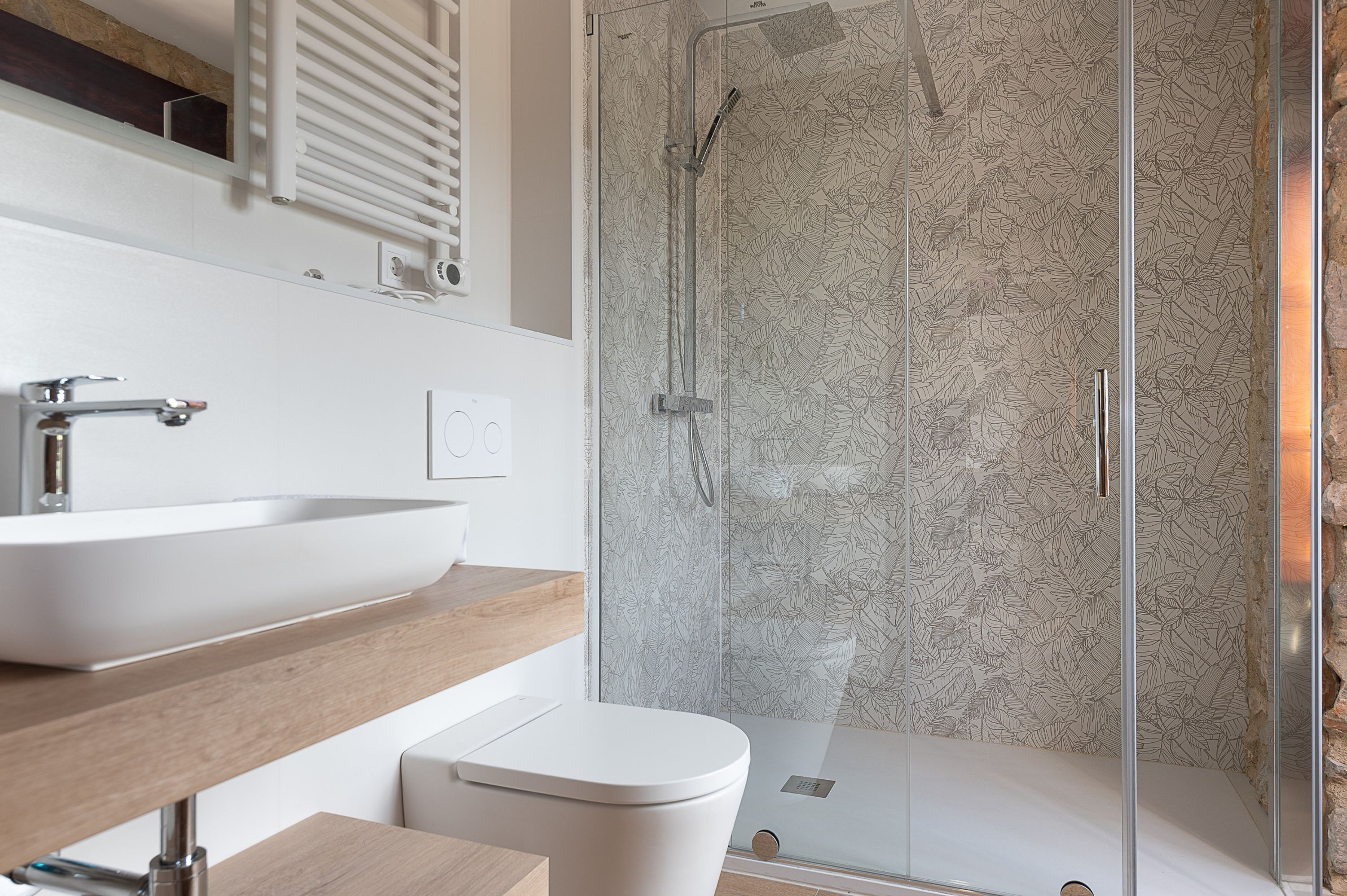 Une salle de bain moderne avec un grand lavabo blanc, des toilettes et une douche séparée par une paroi de verre.