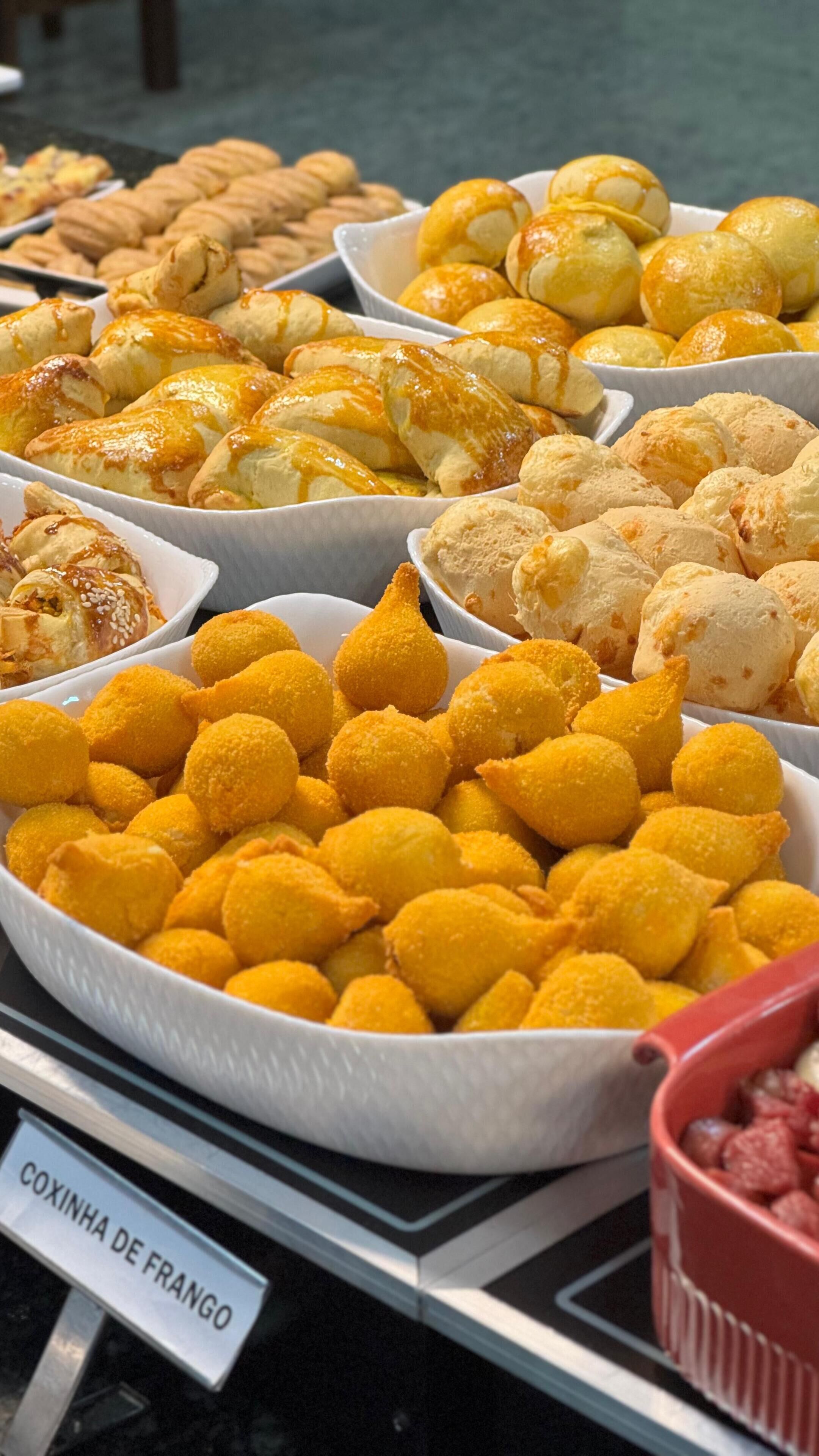 A variety of baked goods displayed in bowls, including golden-brown pastries and yellow croquettes.