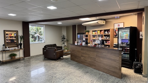 A reception area with a counter, seating, a large window, and a vending machine.