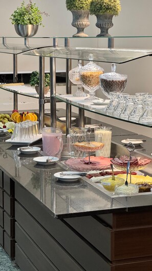 A buffet setup with various food items and beverages. - Hotel Zandona (Blumenau)