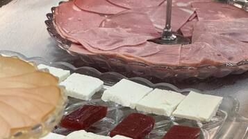A buffet with various food items including sliced meats, cheeses, and fruits.