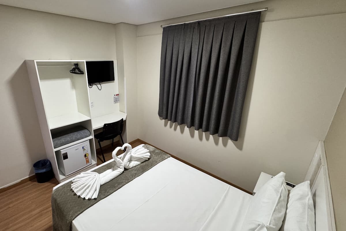 Une chambre d’hôtel comprenant un lit, un bureau, une armoire et un espace douche.