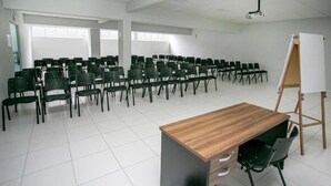 A classroom with rows of chairs, a wooden desk, and a whiteboard. - Hotel Zandona (Blumenau)