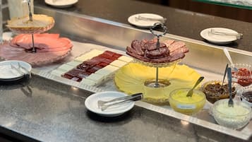 A buffet with various food items including sliced meats, cheeses, and dips.