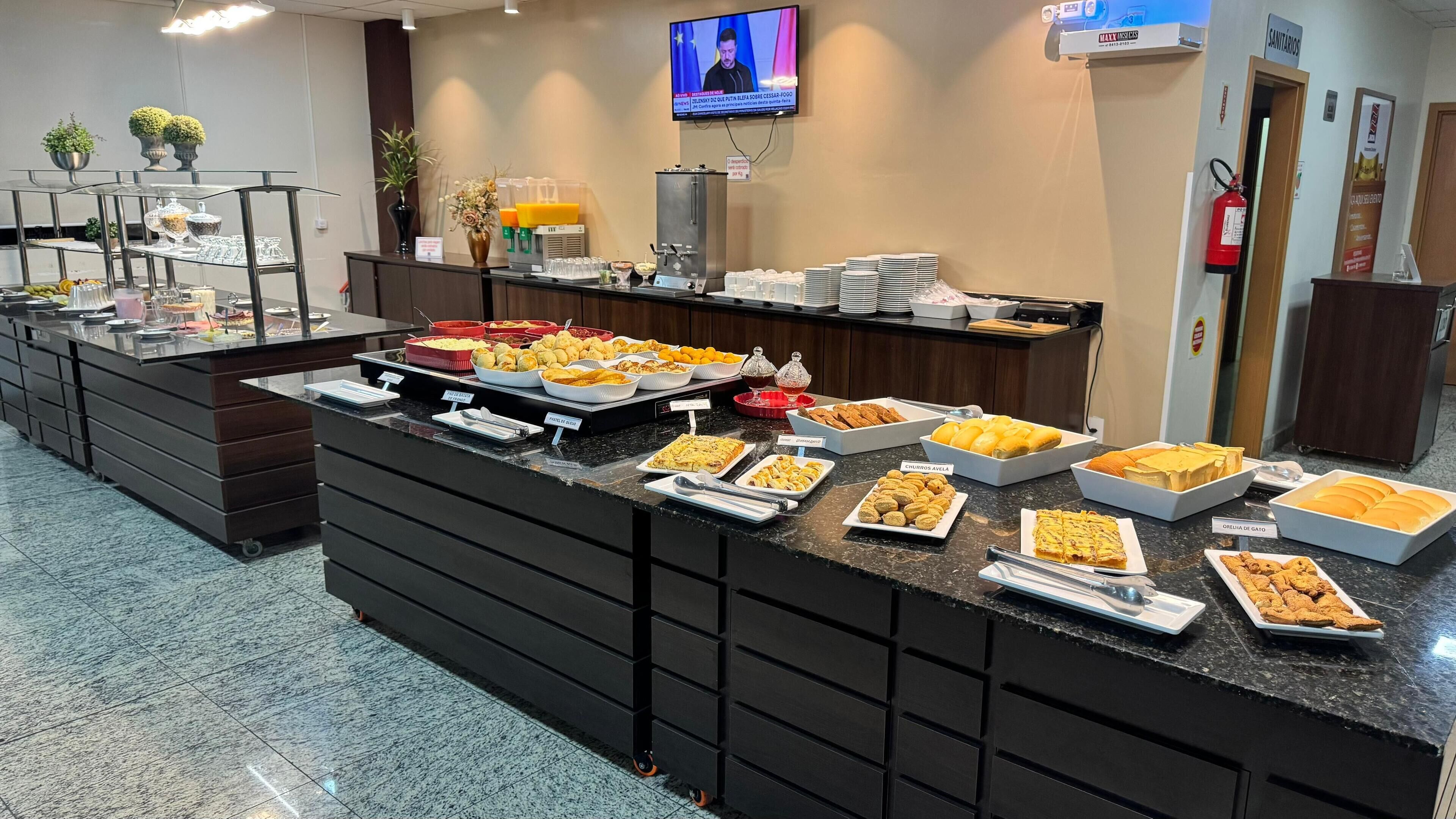 Zona de bufé con diversas opciones de comida y una pantalla de televisión al fondo.