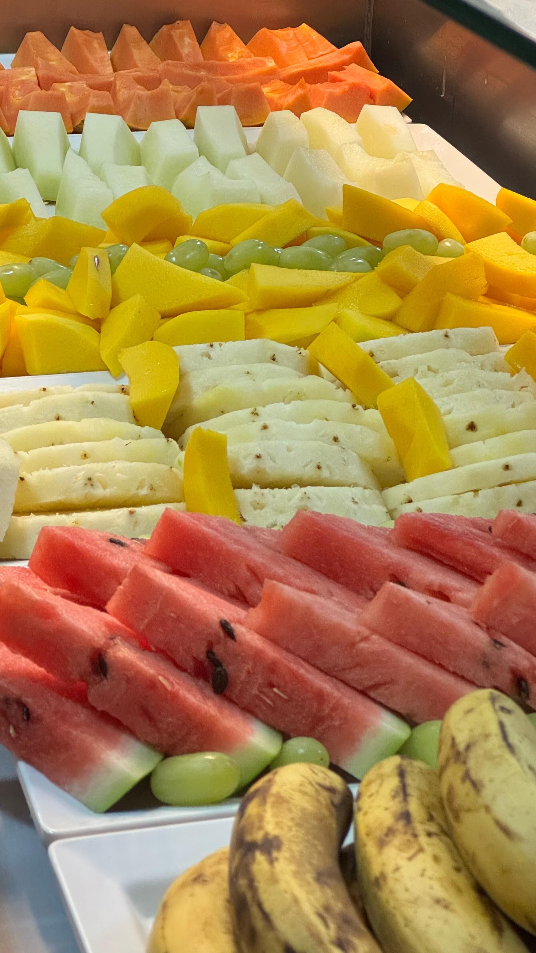A fruit platter with various types of fruits including watermelon, mango, and grapes.