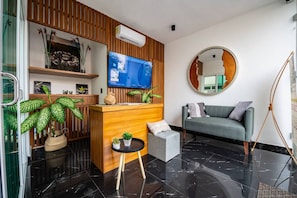 A modern reception area with a wooden reception desk, a flat-screen TV, and a round mirror on the wall.