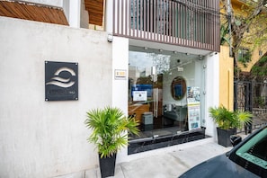 A building with a glass entrance, a sign reading "CENTRAL 40", and two potted plants on the sidewalk.