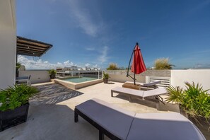 A rooftop terrace with a swimming pool, lounge chairs, and potted plants. - Stylish 1BD w/ Rooftop Pool, Walk to Beach +5th (Playa del Carmen)