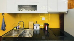 Una cucina con mobili bianchi, un piano di lavoro nero, un lavello, una macchina per il caffè e un portachiodi.