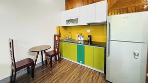 Una cucina compatta con un pensile in legno, un frigorifero bianco e un piccolo tavolo con sedie.