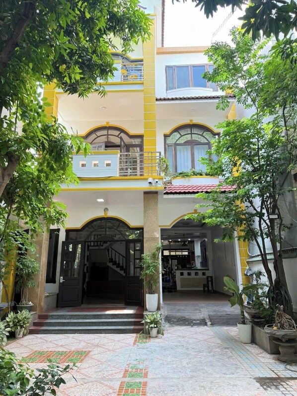 A two-story building with a central entrance, potted plants, and tiled flooring. - Baliza Home (Da Nang)