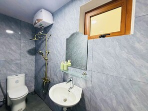 A bathroom with a toilet, sink, shower, and a mirror. - Baliza Home (Da Nang)