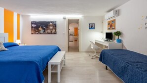 Une chambre avec deux lits, un bureau, une chaise et un ordinateur.