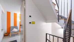 Un escalier avec une rampe en métal, une chaise avec un coussin et un panneau jaune sur le mur.