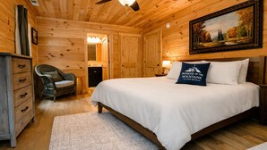 A wooden cabin-style bedroom with a bed, a chair, a dresser, a ceiling fan, and a painting on the wall. - Wild Rose Cottage with Full Access to Rumbling Bald Amenities in Lake Lure! (Lake Lure)