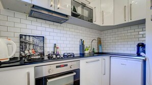 A compact kitchen with white cabinets, a black countertop, a gas stove, a built-in oven, and a dishwasher. - 3rd floor, balcony, parking, tv, ski locker, 35m², Morzine (Morzine)