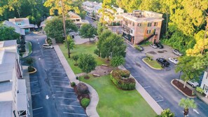An aerial view of a residential area with a parking lot, houses, and trees.