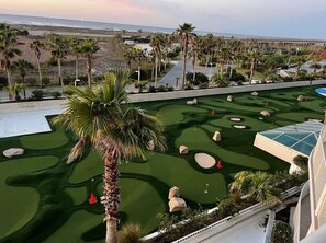 Un campo de golf con vista al océano y palmeras.