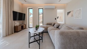 Una sala de estar moderna con un sofá, una mesa de centro, un televisor y una ventana con vistas al exterior.