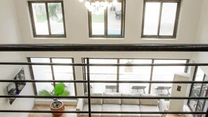 A room with a large window, a sofa, and a potted plant. - The Escape Ghana - Garden Villa (Accra)