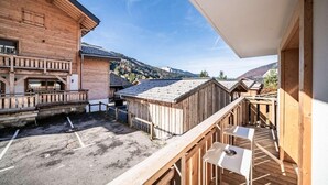 Ein Holzhaus mit Balkon, einer kleinen Außen-Sitzgelegenheit und Blick auf die Berge.