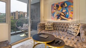 A modern living room with a tufted sofa, a round coffee table, and a glass-enclosed balcony.