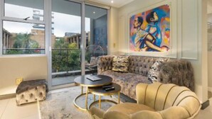 A modern living room with a large window, a sofa, a round coffee table, and a painting on the wall.