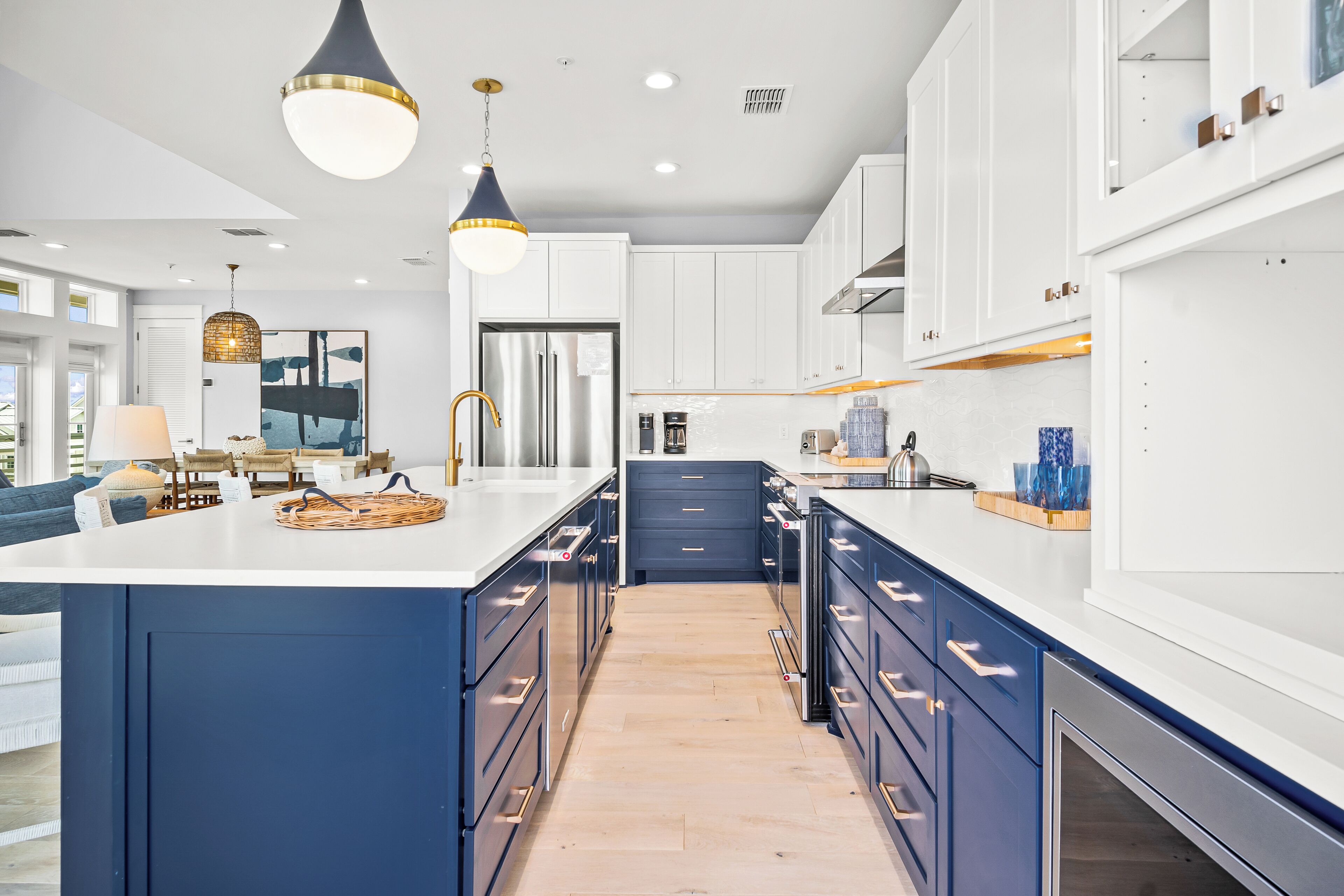 A modern kitchen with white cabinets, blue accents, and stainless steel appliances.