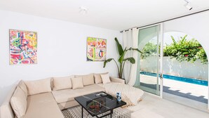 A modern living room with a beige sofa, a glass coffee table, and two abstract paintings. - Le Duplex du Golden Tulip (La Marsa)