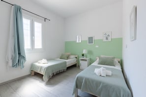 A bedroom with two beds, a window, a nightstand with a lamp, and wall art. - GuestHost - Charming 95 sqm apartment located on the ground floor of a recently renovated building, able to accommodate up to 5 people. The property is located on Via Livornese, a few meters from the Ciclopista del Trammino, a cycle path that connects  (Pisa)